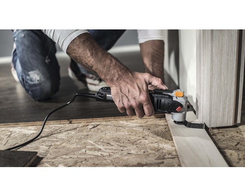 Un bărbat folosește un instrument multifuncțional pentru a tăia o bucată de lemn