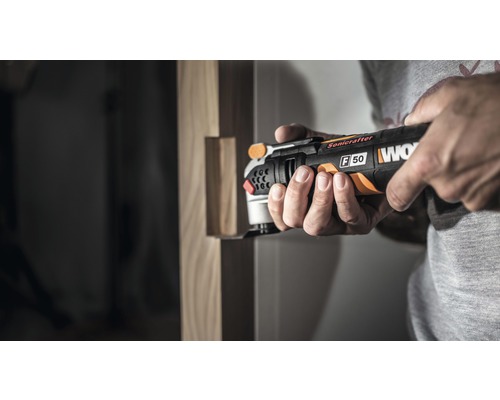 Un bărbat folosește o șlefuitoare multifuncțională Worx pentru prelucrarea lemnului.