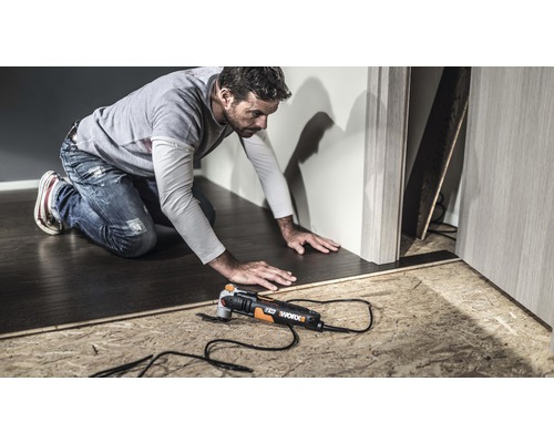 Un bărbat lucrează cu un instrument multifuncțional Worx pe o podea.