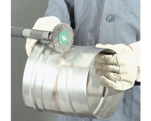 O persoană curăță o țeavă metalică cu o perie de sârmă.