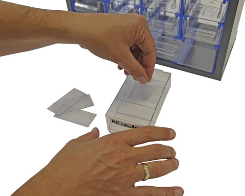 O persoană umple un sertar al unei cutii de sortare cu etichete.