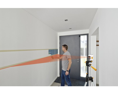 Bărbat folosind un laser liniar pentru a picta un perete