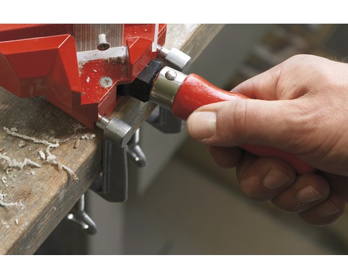 Mână care operează menghina de colț pe piesa de lucru