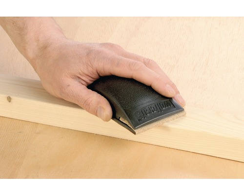 Mână șlefuind o șipcă de lemn cu un șlefuitor manual