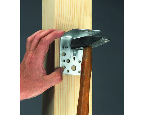 Conectorul unghiular cu o singură mână este fixat de un stâlp de lemn cu un ciocan.