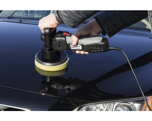 O persoană lustruiește o mașină cu o mașină de lustruit.