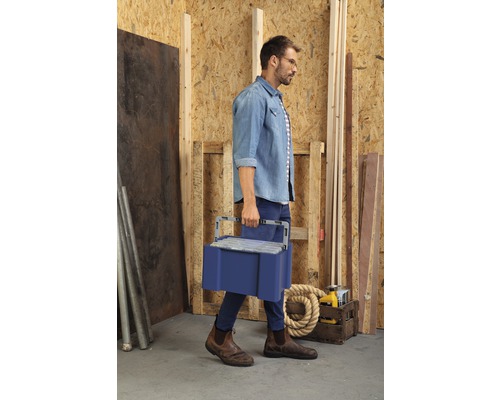 Un bărbat care poartă o cutie cu scule într-un atelier