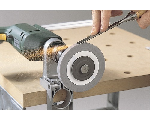 O piatră de polizor este atașată la o mașină de găurit în timp ce o persoană ascute o daltă pe ea și apar scântei.