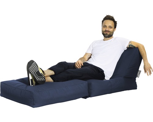 Bărbat relaxându-se pe o canapea extensibilă albastră.