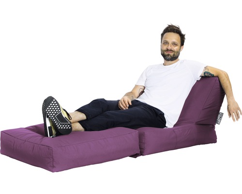 Bărbat relaxându-se pe o insulă de ședere violetă cu suport pentru picioare.