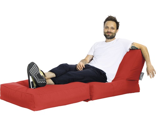 Bărbat relaxându-se pe un puf roșu cu suport pentru picioare