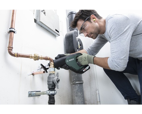 Artizan care taie o țeavă de cupru cu un fierăstrău electric cu acumulator Bosch