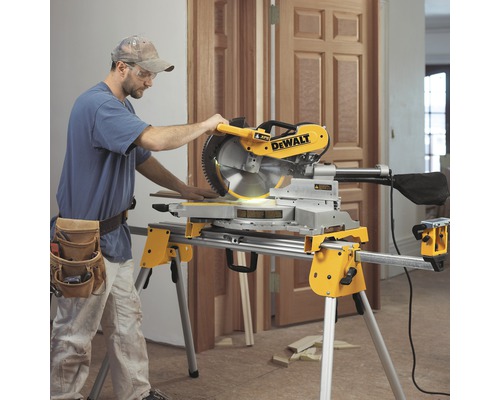 Un bărbat operează un ferăstrău circular DeWalt pe un suport într-o cameră.
