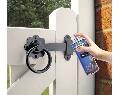 Vopsea spray este aplicată pe o poartă de grădină