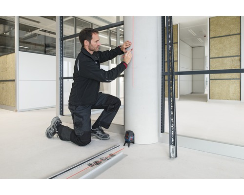 Artizan cu laser cu linii încrucișate la montarea unei substructuri metalice în construcții interioare.