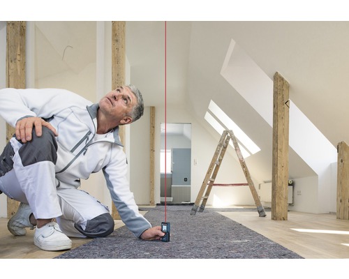 Artizan folosește un telemetru laser într-un pod pentru a efectua măsurători precise.