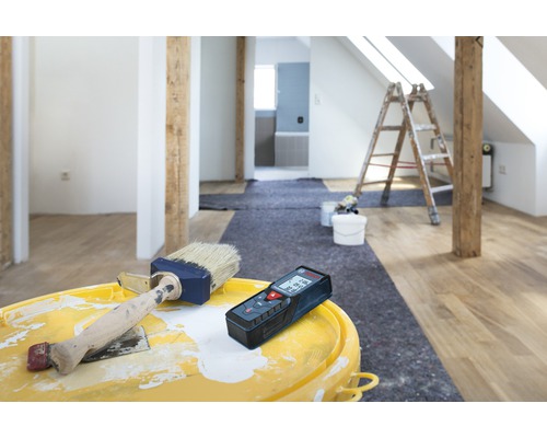 Renovare cameră cu telemetru laser, vopsea și pensulă pe o găleată