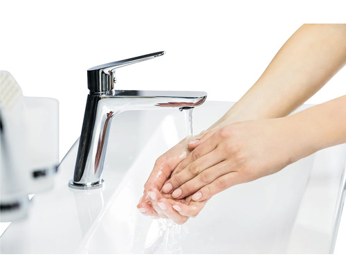 Femeie se spală pe mâini sub un robinet într-o chiuvetă