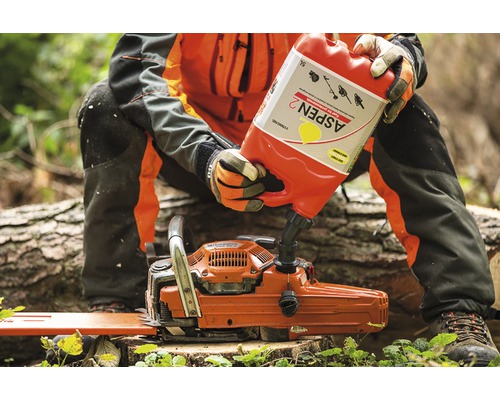 O persoană toarnă combustibil dintr-un recipient Aspen 2 într-un motoferăstrău.