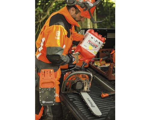 Un bărbat în haine de lucru umple un motoferăstrău cu combustibil Aspen 2.