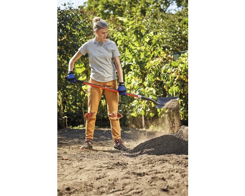 O femeie sapă pământ cu o lopată într-o grădină.