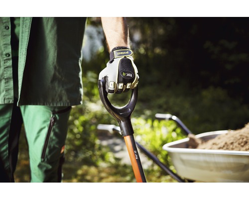 Grădinar ținând o lopată cu mănuși, roabă în fundal