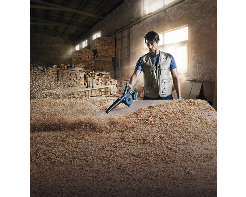 Bărbat curățând bancul de lucru cu un suflător de frunze de așchii de lemn