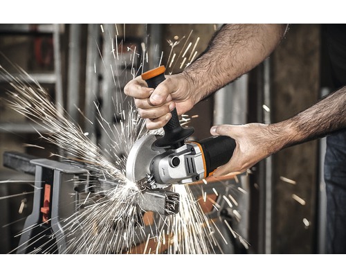 O persoană taie o bucată de metal cu un polizor unghiular, scânteile zburând.