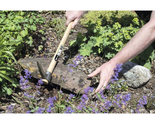 Persoană care lucrează în grădină cu un târnăcop cu mâner de lemn.