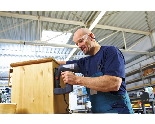 Artizan fixând lemn cu un capsator electric