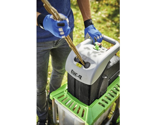 O persoană introduce crengi într-un tocător de marca for_q.