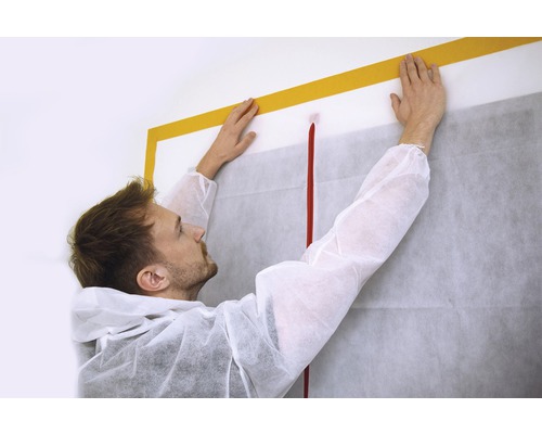 Artizan care fixează folie de protecție împotriva prafului cu bandă adezivă pe perete