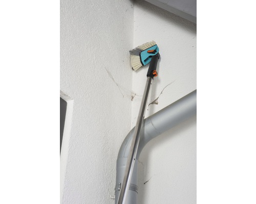 Perie de fațadă cu mâner telescopic utilizată pe un perete al casei