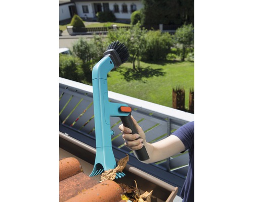 Persoană care curăță jgheabul cu un curățător de jgheaburi