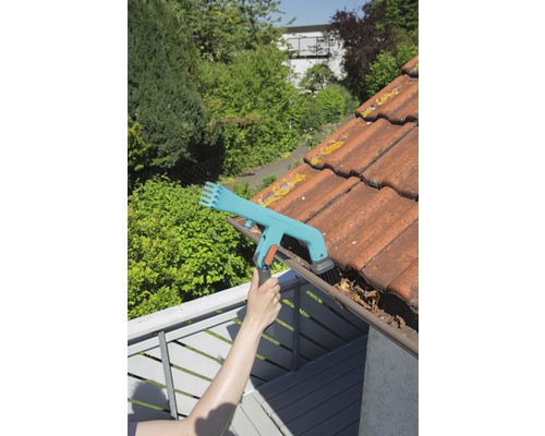 Persoană care curăță jgheabul cu un dispozitiv de curățat jgheaburi