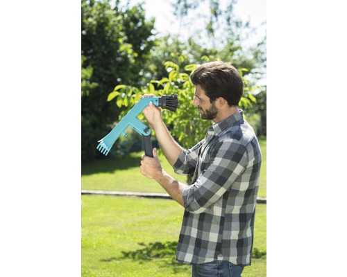 Un bărbat din grădină folosește un culegător de fructe pentru recoltare.