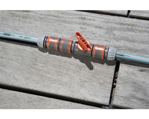 Robinet de reglare Gardena conectat la un furtun de grădină pe o masă de lemn