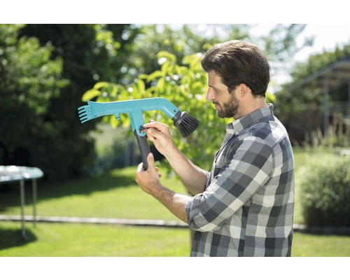 Un bărbat operează o perie de jgheab în grădină.