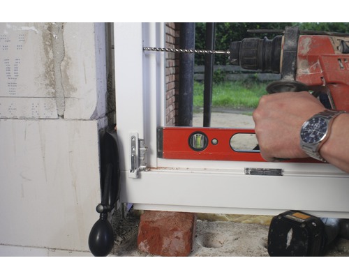 O fereastră este instalată cu o mașină de găurit și un boloboc.