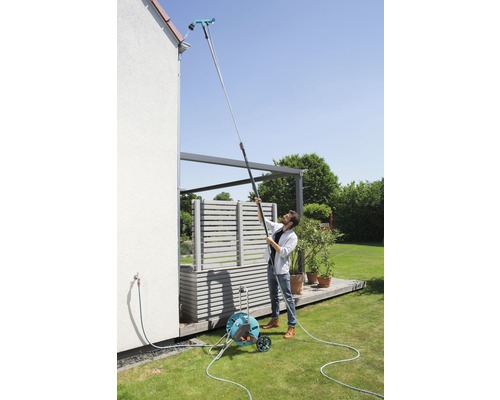 Bărbat curăță jgheabul cu un dispozitiv de curățat jgheaburi pe un mâner telescopic