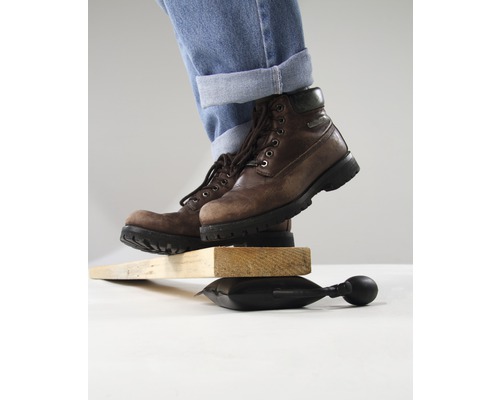 Persoană cu cizme, echilibrată pe pernă de aer între bucăți de lemn