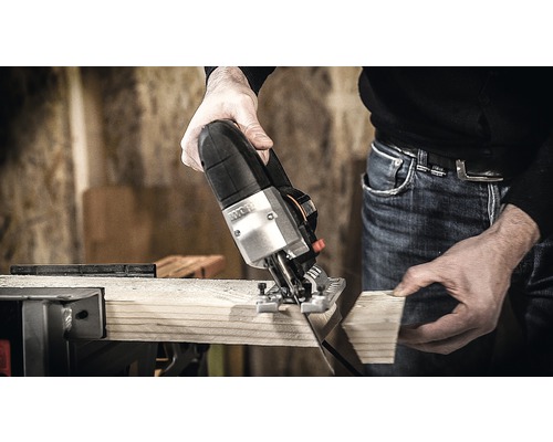 Un fierăstrău vertical taie o scândură de lemn.