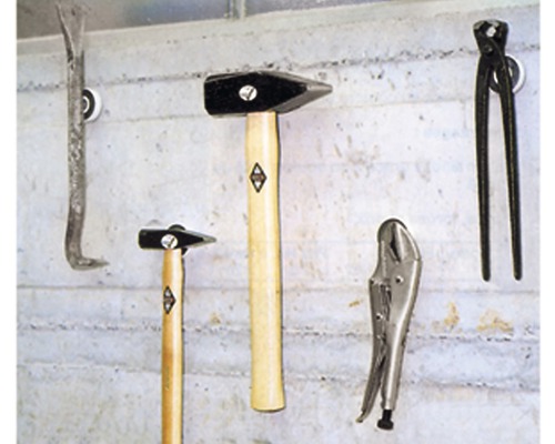 Diverse unelte, inclusiv un ciocan, o rangă, un clește și o menghină cu șurub, sunt agățate pe un perete