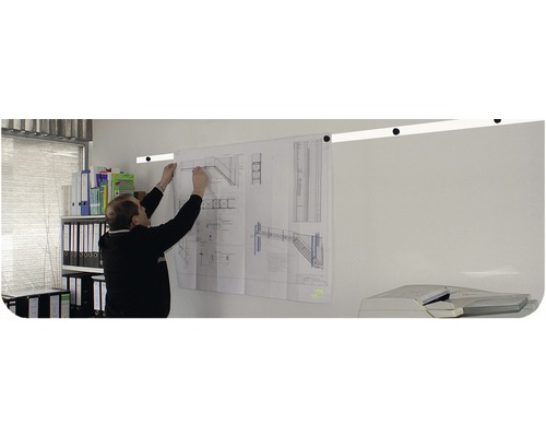 Un bărbat fixează un plan de construcție cu motive de scări pe o șină de perete într-un birou.