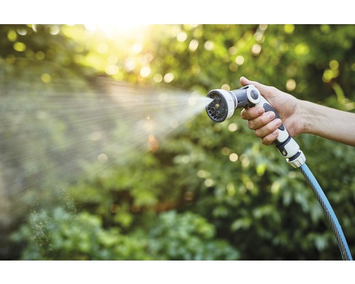 O mână ține un pulverizator de grădină din care iese apă.