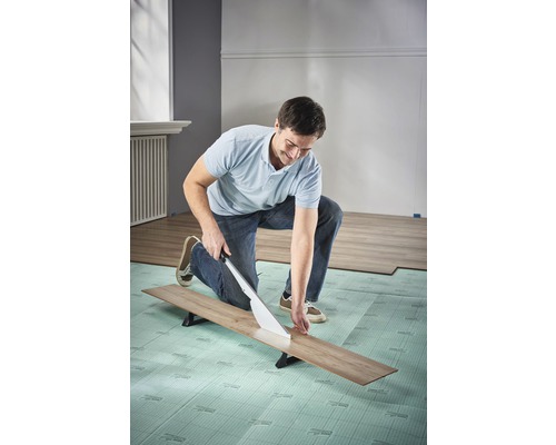 Bărbat taie laminat cu un tăietor de laminat pe izolație fonică