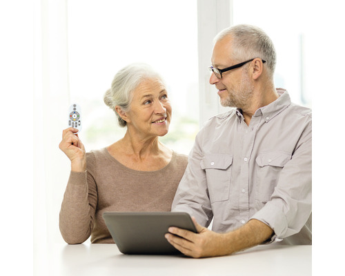 Cuplu în vârstă care operează o tabletă cu o telecomandă.