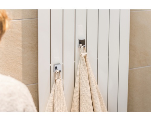 Calorifer alb cu două prosoape și cârlige cromate în baie.