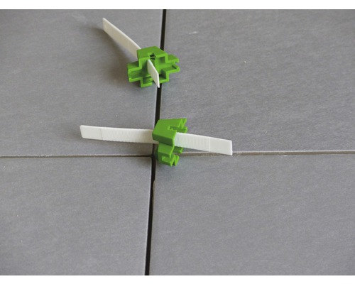 Sistem de nivelare a plăcilor ceramice cu pene verzi și urechi de tragere albe pe plăci