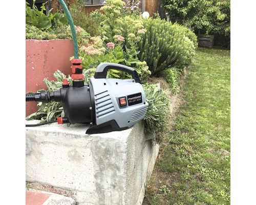 Pompă de grădină cu furtun pe un soclu de beton în grădină